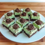Top view of sliced mint cheesecake bars with Oreo crust on a white marble surface